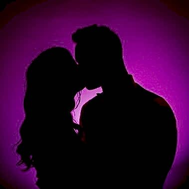 Silhouette of a couple kissing against a purple background, captured by a professional wedding photographer.