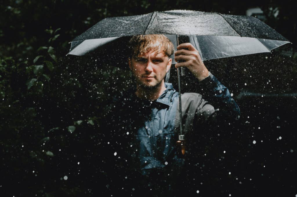 Person under umbrella in rainy garden
