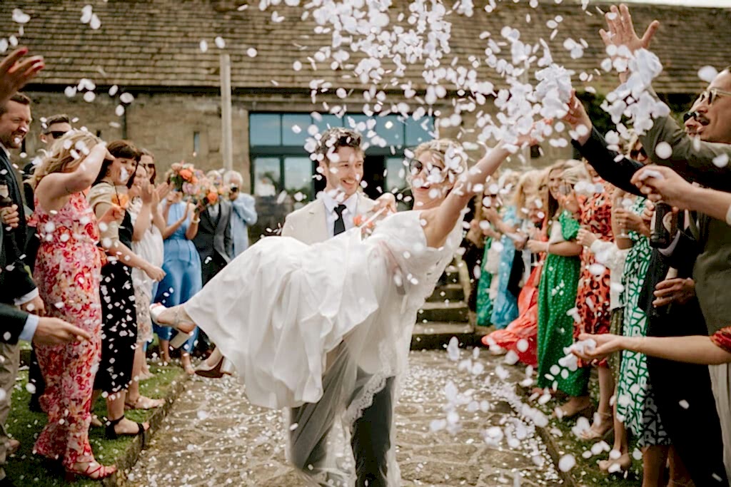 Wedding couple surrounded by confetti and guests.