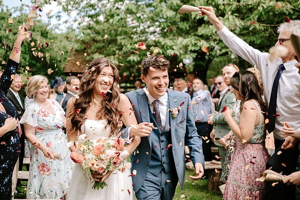 Bride and groom surrounded by guests throwing confetti.
